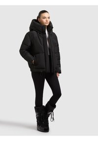 Chaqueta acolchada negra con una gran capucha desmontable, cierres de cremallera y broches, bolsillos laterales y cordones elásticos en el dobladillo.