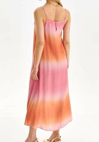 Lange, mouwloze jurk met een gradient ontwerp van roze naar oranje, gemaakt van lichtgewicht stof, met een lage rug en subtiele zijsplit.