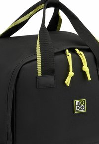Zaino nero in tessuto testurizzato, con dettagli in metallo giallo, manici a strisce doppi e etichetta con logo sulla parte anteriore.