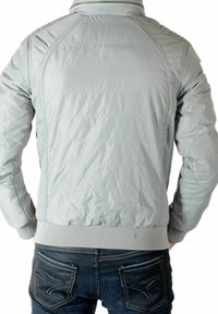 Lysegrå polstret jakke med ribbet krave og manchetter, med en glat tekstur og diagonale syningsdetaljer på ryggen.
