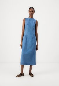 Vestido de franelilla, sin mangas, a la altura de la rodilla, de color azul claro, con un escote redondeado y detalles de costura sutil. Combinado con bailarinas de estampado de leopardo.