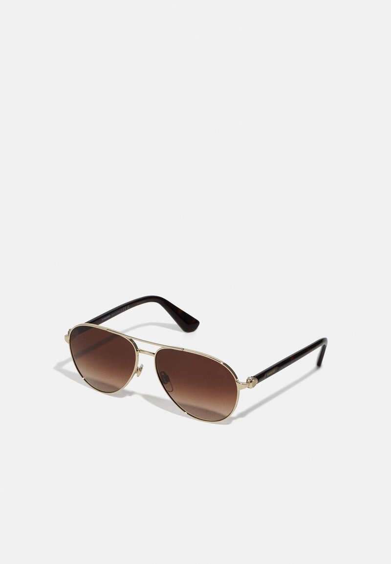Hnědé sluneční brýle typu aviator s zlatým kovovým rámem a tmavými želvovinovými rámovými nohami. Obsahují jemné detaily na rámu a pantě.
