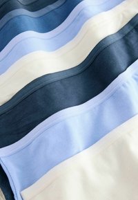 Bomuldsstoflag i forskellige nuancer af blå, creme og marineblå. Glat tekstur med en let glans og kontrasterende farvede kanter.