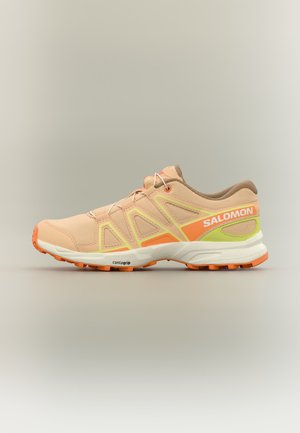 Zapatilla de running Salomon beige y naranja con suela naranja, detalles en amarillo neón, suela Contagrip y entresuela blanca, mostrada sobre un fondo neutro.