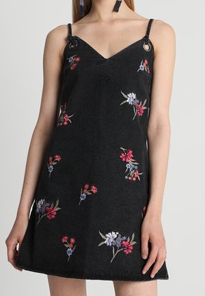 Robe noire sans manches en ligne A avec fines bretelles et fleurs brodées roses, rouges et violettes dispersées sur le tissu.