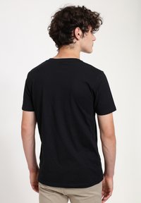 Black cotton t-shirt with short sleeves, round neckline, and a plain design, viewed from the back, showing a smooth texture and fit.