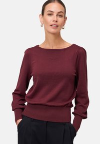 Maglione a maniche lunghe color bordeaux con scollatura ampia, polsini a costine e vita aderente. Morbido, con una texture liscia e una vestibilità rilassata.
