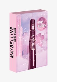 Mascara Maybelline dans un tube violet, emballé dans une boîte rose avec un fond de ligne d'horizon de ville et le texte "Joyeuses Fêtes".
