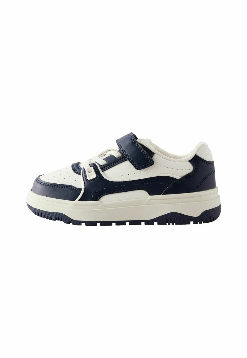 White and navy sneakers featuring a smooth leather upper, perforated toe, adjustable strap, padded collar, and textured rubber sole.