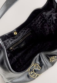Zwarte leren totebag met een textuurafwerking, voorzien van een gouden drukknoopsluiting, een binnenvak met rits en een voering met luipaardprint.