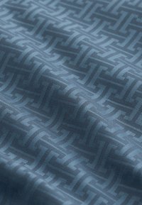 Tissu bleu avec un motif entrelacé répétitif, présentant une texture lisse et un tissage régulier. Les couleurs varient du bleu foncé au bleu clair.