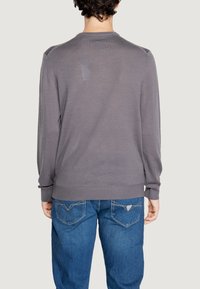 Maglione grigio a maniche lunghe con tessuto a trama e scollatura rotonda, abbinato a jeans in denim blu con un design a tasca posteriore a forma di V.