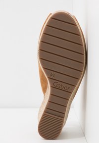 Semelle d'une chaussure compensée marron avec une bande de roulement en caoutchouc texturé, une semelle intermédiaire en corde de jute, et la taille 4½ embossée au-dessus du nom de la marque Gabor.