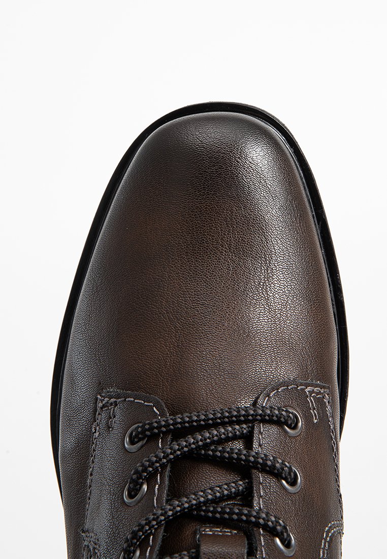 Zapato de cuero marrón con punta redonda, superficie texturizada, cordones negros y un diseño cosido a lo largo de los laterales.