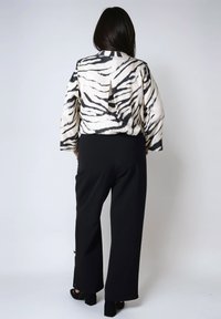 Zebra print cropped top with long sleeves, cutout detail at the back, paired with black wide-leg pants and high-heeled shoes.