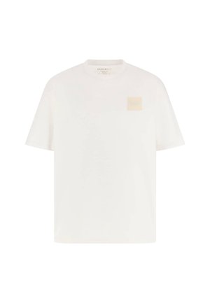 T-shirt en coton blanc à manches courtes, col rond, avec un patch logo carré beige sur la poitrine gauche. Texture lisse, coupe décontractée.