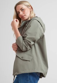 Light olive-green waterproof jacket with a hood, relaxed fit, two-button closure, and decorative flap pockets. Textured fabric with smooth finish.