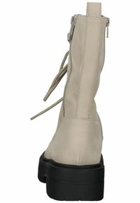 Beige enkellaarsje met een glad leren afwerking, voorzien van een ritsluiting, veters en een chunky zwarte zool. Achteraanzicht getoond.