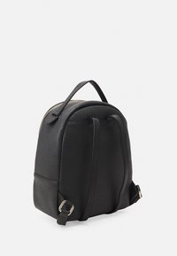 Zaino nero realizzato in un materiale testurizzato. Parte superiore arrotondata, spallacci regolabili e chiusura con zip con dettagli in hardware dorato.