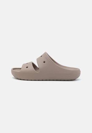 Beige slip-on Crocs sandal med to brede ventilationsremme og en tekstureret sål for greb, vist i sideprofil.