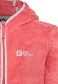 Coral fleece jacket with a hood, front zipper, and white trim. Features "Jack Wolfskin" logo in white on the left side. Soft texture.
