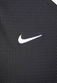 Sort atletisk stof med en struktureret overflade. Karakteriseret ved et hvidt Nike swoosh-logo til venstre, der skaber en dynamisk kontrast.