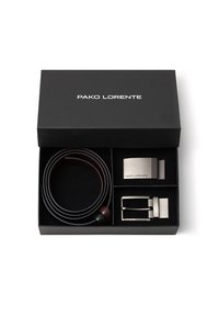 Czarny pudełko na prezent zawierające brązowy skórzany pasek, srebrną metalową klamrę i metalowy element dekoracyjny. Widać branding "PAKO LORENTE".