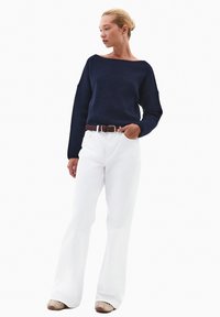 Granatowy sweter dzianinowy z szerokim dekoltem, białe spódniczki flare, brązowy pasek i beżowe buty. Gładka tekstura z codziennym stylem.