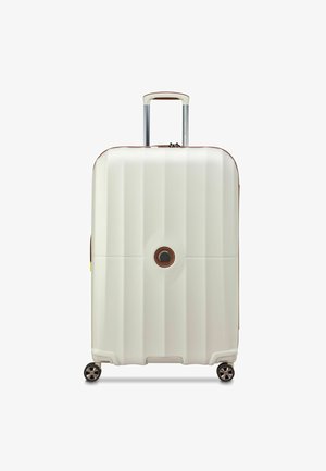 Hard-shell suitcase in cream color with vertical ribbing, brown accents, retractable handle, and four wheels for mobility.