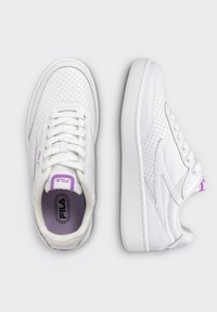 Baskets blanches Fila avec détails perforés vues de dessus et de côté, avec lacets blancs et accents de logo violets.