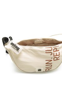Riñonera beige con texto marrón que dice "CORRE. SALTA. REPITE." Cuenta con cierre de cremallera, correa negra y etiqueta de logo. Tejido suave y texturizado.
