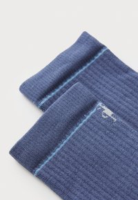 Calcetines en color navy con textura acanalada. Cuentan con una franja azul claro en el borde superior. Están hechos de un tejido de punto suave para mayor comodidad y calidez.