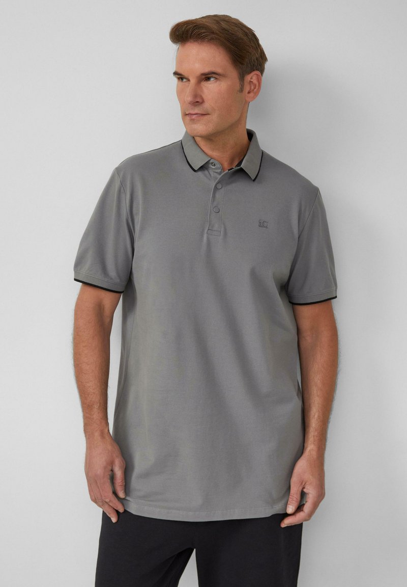 Grijze polo met een gladde stof, voorzien van een kraag, een drieknoopssluiting en contrasterende zwarte afwerking op de mouwen en kraag.