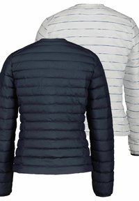 Marinblå fluffig jacka med horisontell söm och långa ärmar, i kombination med en vit randig långärmad tröja i mjukt material.