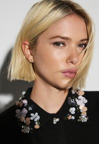 Black garment with a floral collar featuring sequins in pink, blue, and metallic hues, complemented by a small decorative bee accent.