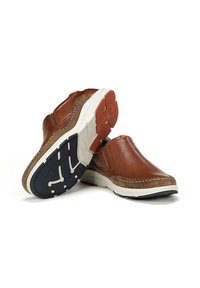 Zapatos de cuero marrón tipo mocasín con un tacón de ante en color beige contrastante, suela en blanco y azul marino, y detalles de costura visibles.