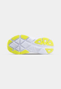 Weiße Sportschuhsohle mit strukturiertem Oberflächen und gelben Gummiakzenten. Verfügt über ein multidirektionales Profilmuster für Grip und Stabilität.