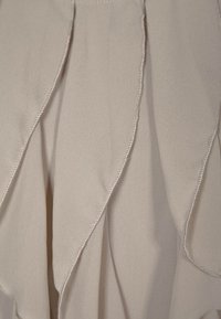 Jasnoszary strój z marszczoną strukturą materiału, z dekoracyjnym przeszyciem wzdłuż krawędzi oraz gładkim, płynącym krojem.