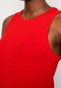 Rode geribbelde tanktop met een hoge halslijn en brede armsgaten, met een aangesloten ontwerp en een gladde textuur.