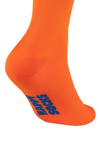 Pomarańczowa skarpetka o rypsowej fakturze, z niebieskim logo nadrukowanym z boku. Skarpetka jest w długości kostki i dobrze przylega do stopy.