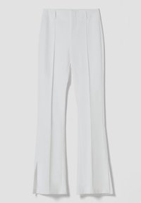 Vita flarebyxor i mjukt tyg, med framfåll och sidoklämmor vid vristerna. Klara linjer och minimalistisk design.