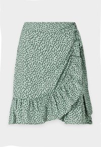 Gonna verde avvolgente con orlo arricciato, caratterizzata da piccoli motivi a pois neri. Realizzata in tessuto leggero per un design fluido.