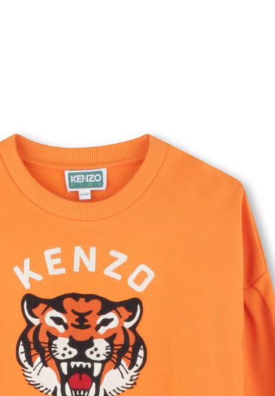 Sweatshirt orange avec col rond côtelé, présentant un grand motif de tête de tigre brodé et un texte blanc indiquant "KENZO". Texture en coton doux.