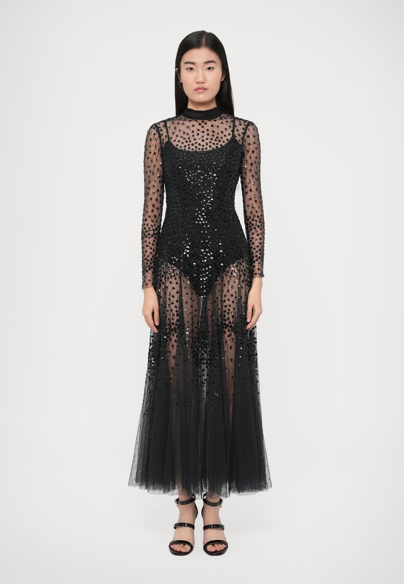 Black sequin dress with long sleeves, fitted bodice, sheer tulle skirt, and a high neckline. Features a semi-transparent design.