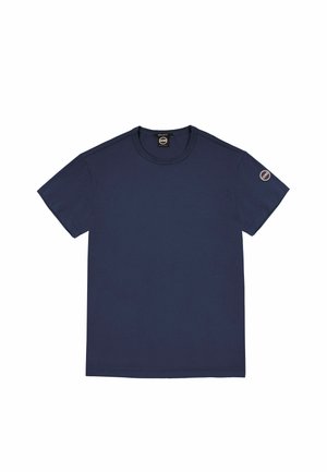 Camiseta de manga corta en azul marino con cuello redondo, parche con logo circular pequeño en la manga izquierda y etiqueta de la marca en el interior del cuello.