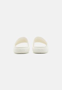 White rubber slide sandals with open back, featuring the brand "Levi's" embossed on the outsole and a textured surface for grip.
