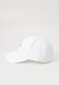 Witte katoenen baseballcap met een gebogen rand, ronde bovenkant en geborduurd logo aan de voorkant; voorzien van ventilatiegaten en een verstelbare band.