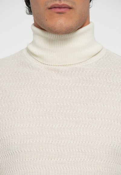 Tej turtleneck pulóver, mely textúrázott, bordázott mintával rendelkezik. Az anyag puhanak tűnik, a nyaknál és a testen szűkített kialakítással.