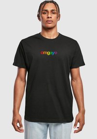 Fekete pamut póló, amelyen a "omgay" felirat multicolor szöveggel és szívvel található. Kerek nyakú, rövidujjú, laza fazonú és egyszerű dizájnnal rendelkezik.