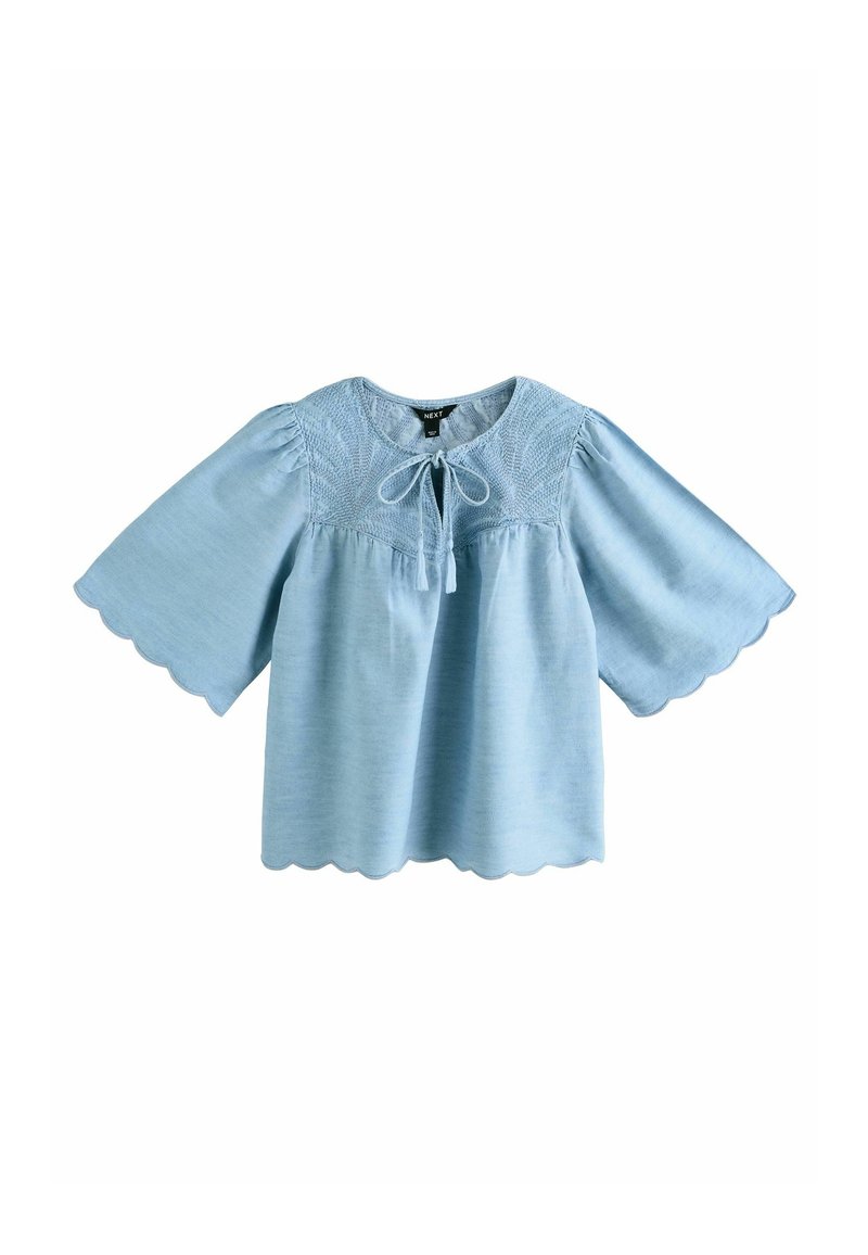 Light blue short-sleeve blouse with a round scalloped neckline, decorative embroidery, and a tied front detail. Soft lightweight fabric.